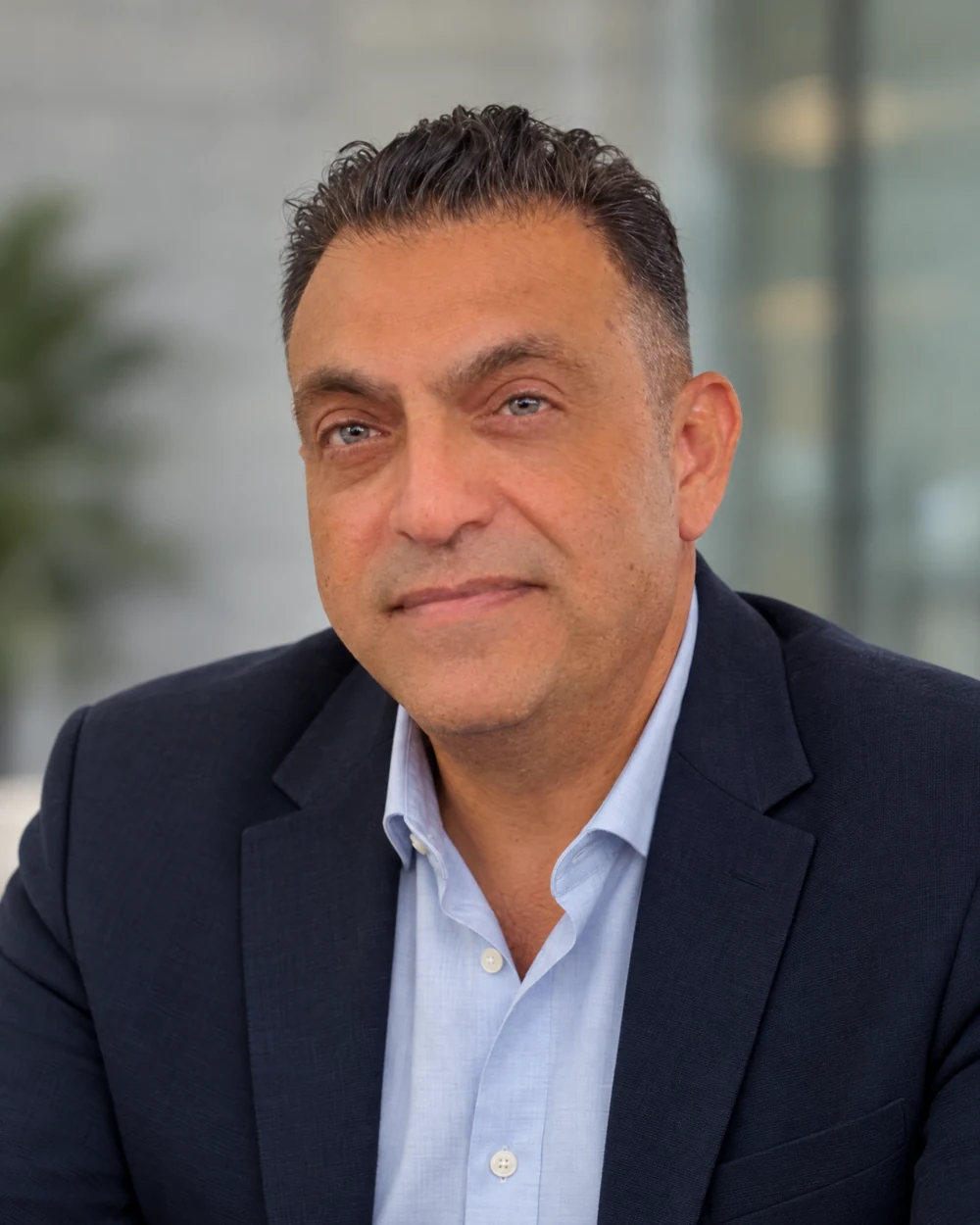 Nicolas Ghrayeb in a navy blazer and open-collar shirt, in a refined contemporary executive portrait